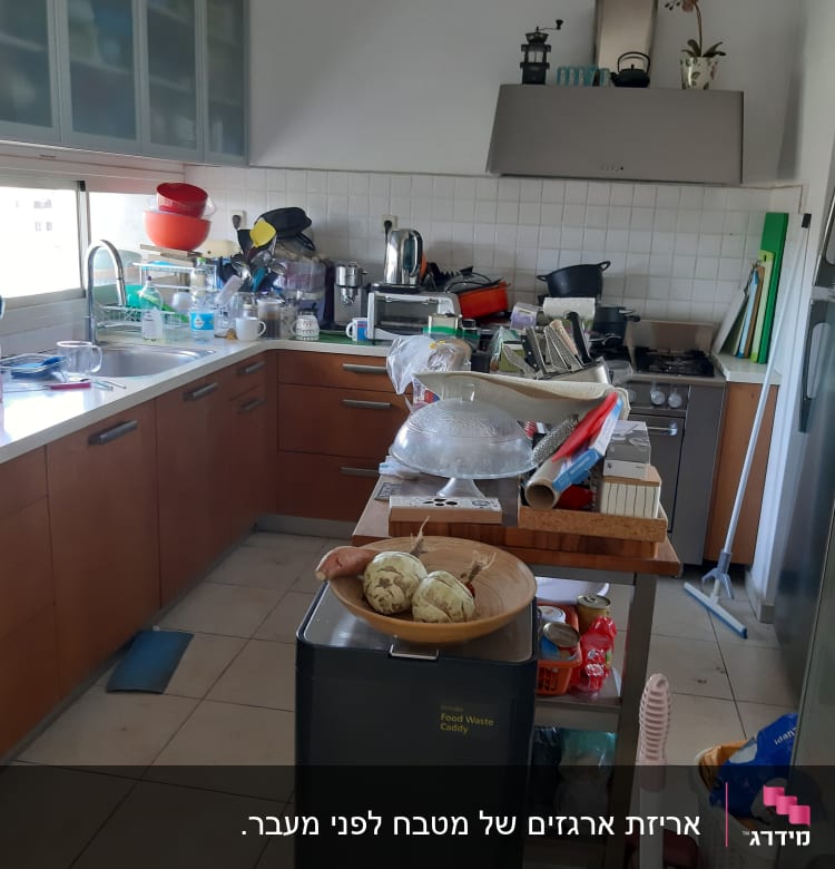 מטבח מבולגן עם כלים על השיש והמדפים